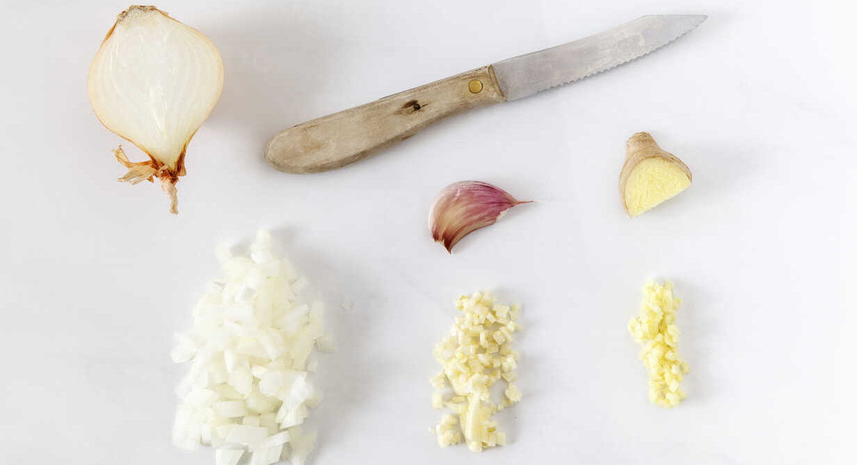 chopped onion ginger garlic and a kitchen knife on white ground EVGF000664 e1658169964527